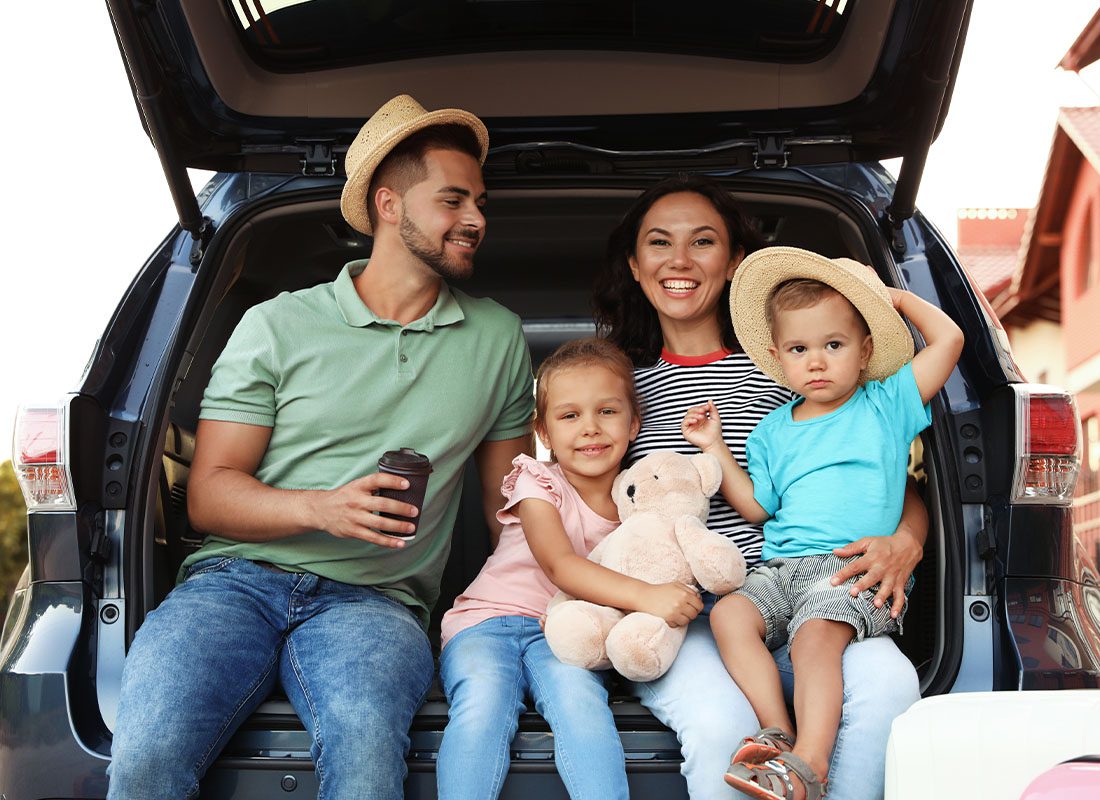 Personal Insurance - Family Portrait Sitting in the Back of Their Family Car Before Setting Out to Take a Road Trip