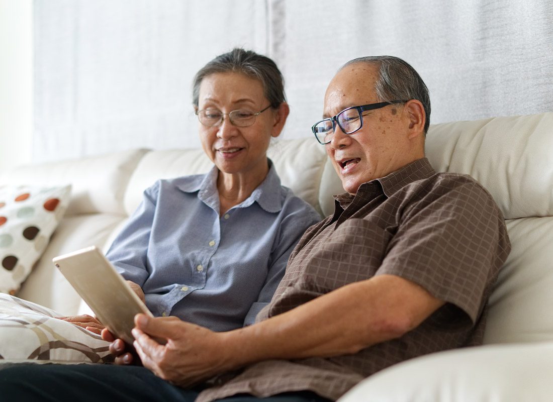 FAQ - Senior Couple Looking at a Tablet While Sitting on the Sofa