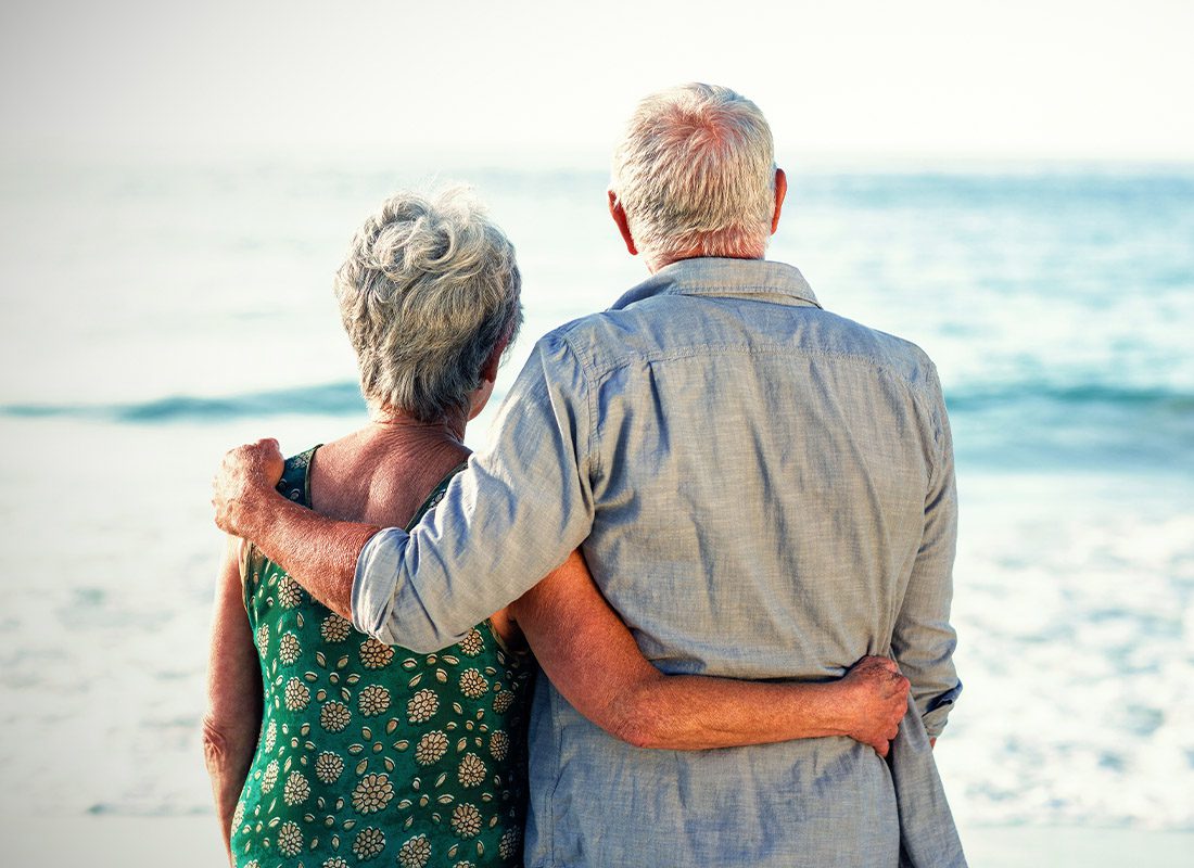 New to Medicare - Rear View of Senior Couple Facing the Ocean on a Sunny Day